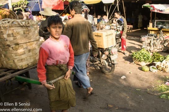 Mandalay, Burma, Myanmar. Zedgyo Market. Boy pulls heavy load.